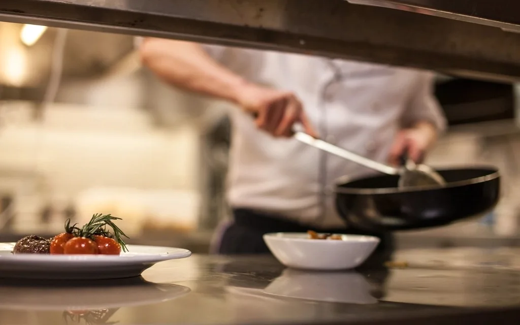 Cozinheiro finalizando um prato durante o serviço